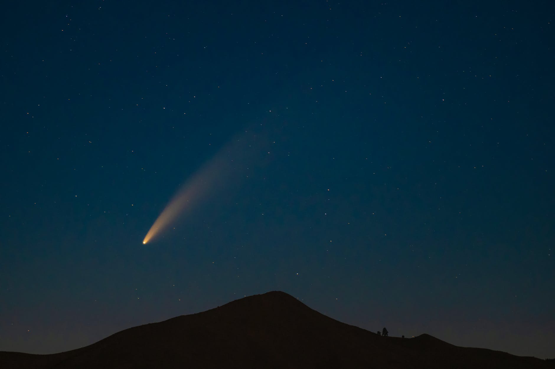 night shot of a mountain and comet in sky